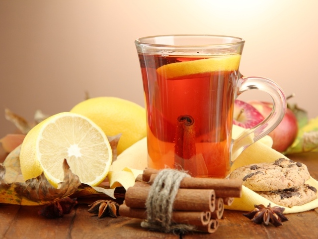 Чашка чая с лимоном и корицей на столе с лимонами
