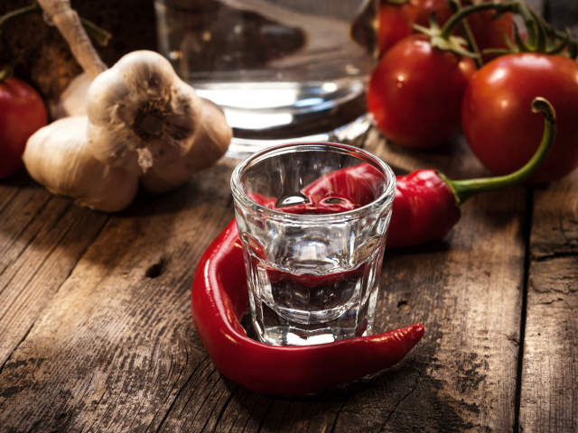 Рюмка водки на столе с красным перцем и чесноком