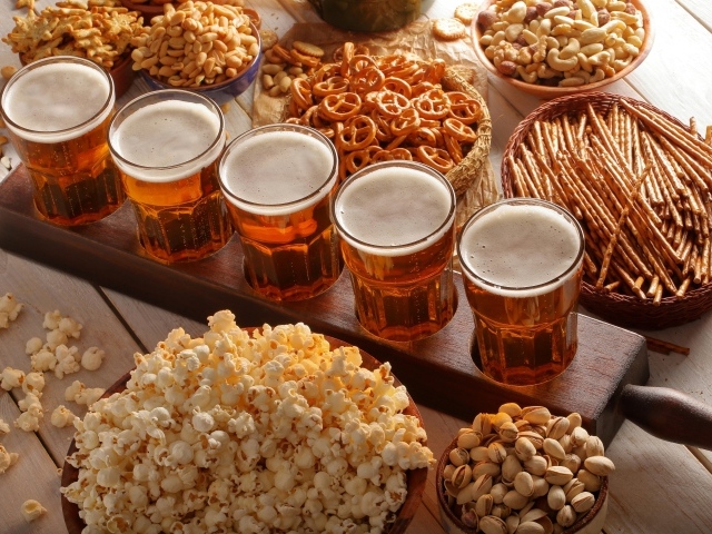 Пиво с орешками, фисташками, попкорном и печеньем на столе