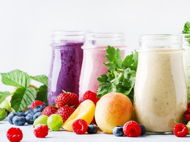 Ягодные смузи в бутылочках на столе с ягодами