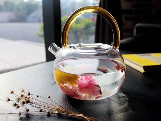 Цветочный чай в стеклянном чайнике на столе 
