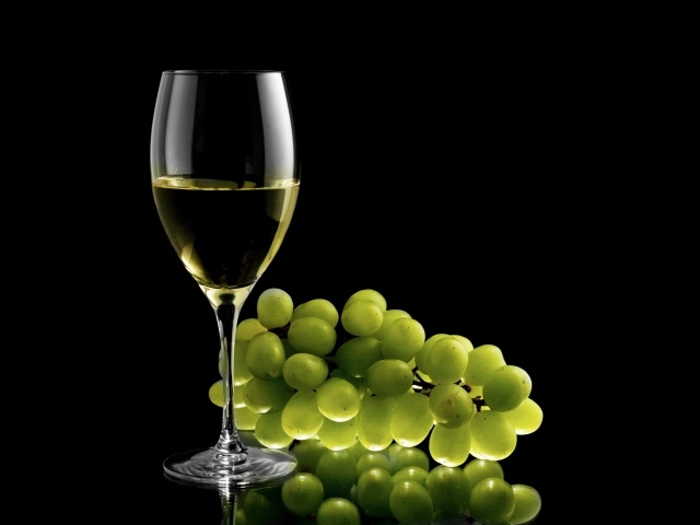 Бокал белого вина с белым виноградом на черном фоне