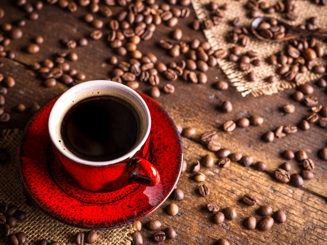 Красная чашка кофе на столе с зернами кофе