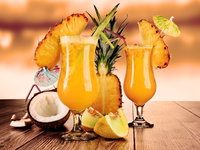 Тропические коктейли на столе со свежими ананасом, кокосом и кусочками дыни