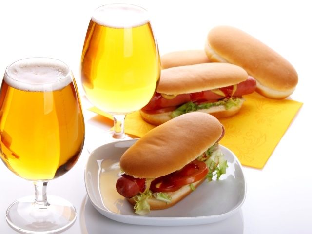 Два бокала пива с хотдогами на белом фоне