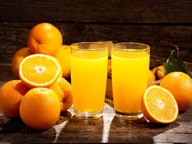 Два стакана свежего апельсинового сока на столе с фруктами