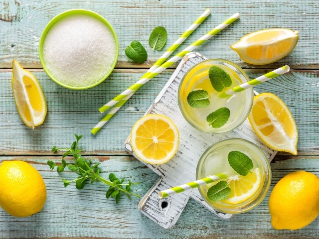 Два стакана с лимонадом, мятой, свежими лимонами и сахаром на столе