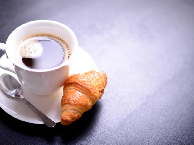 Белая чашка кофе на столе с круассаном
