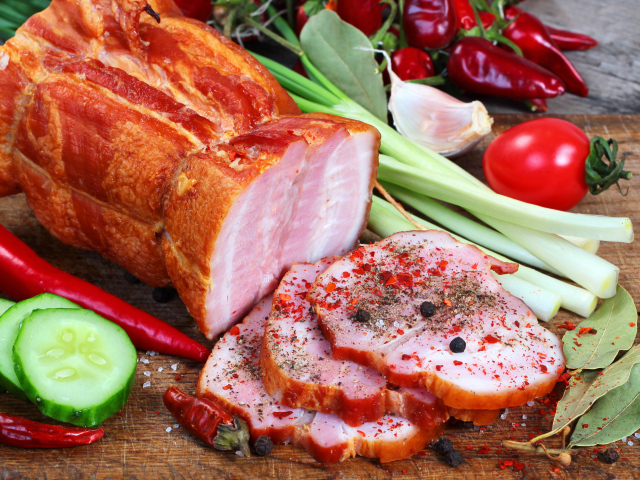 Аппетитная ветчина со специями и свежими овощами на столе