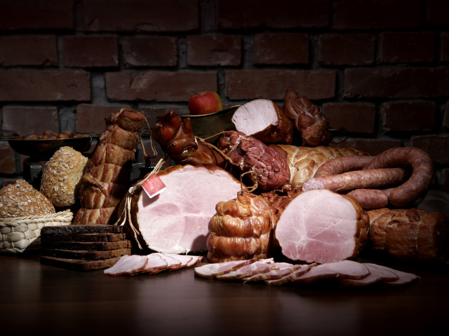 Аппетитные мясные продукты на фоне кирпичной стены 