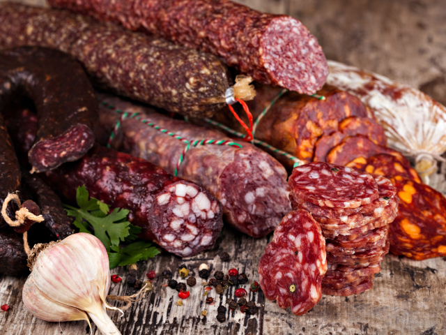 Аппетитная колбаса на столе с чесноком и черным перцем