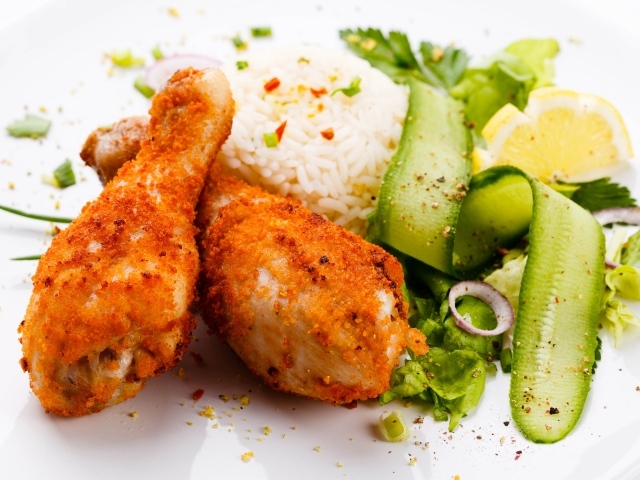 Куриные ножки с рисом и салатом на белой тарелке
