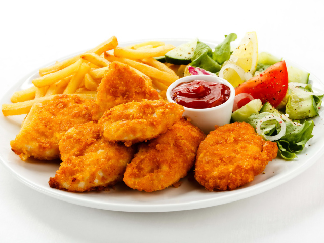 Куриные наггетсы с кетчупом, картофелем фри и салатом на белой тарелке