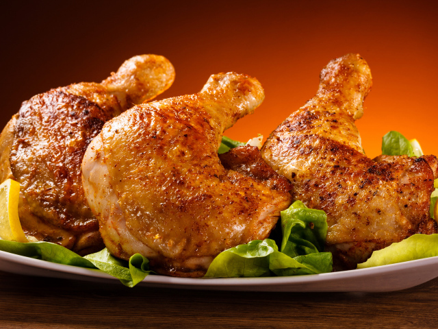 Жареные куриные окорочка на зеленых листьях салата 