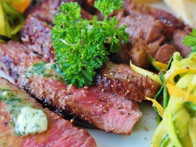 Нарезанный аппетитный кусок мяса с салатом и зеленью петрушки