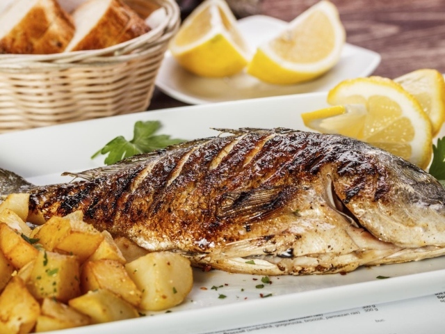Запеченная рыба на тарелке с картофелем и лимоном 