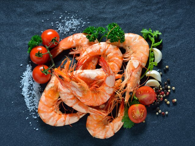 Вареные креветки на столе со специями и  помидорами 