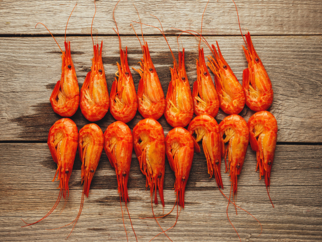 Красные вареные креветки на деревянном столе