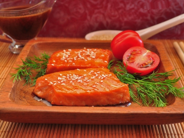 Красная рыба с кунжутом на тарелке с помидорами и укропом