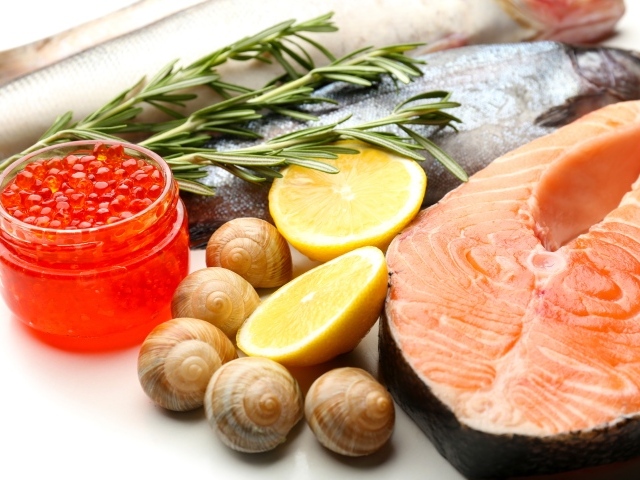 Красная рыба с улитками и красной икрой на столе с лимоном и базиликом