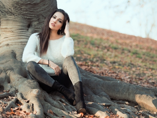 Красивая девушка сидит у дерева