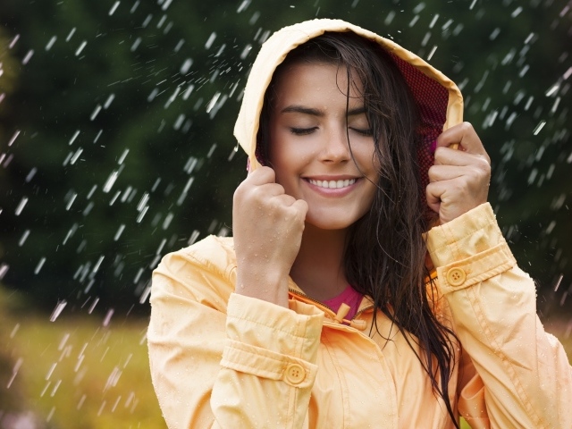 Красивая молодая девушка в желтом плаще стоит под дождем