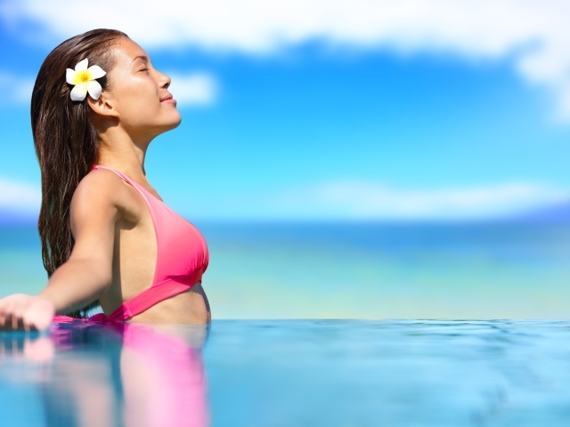 Девушка в розовом купальнике стоит в воде на солнце