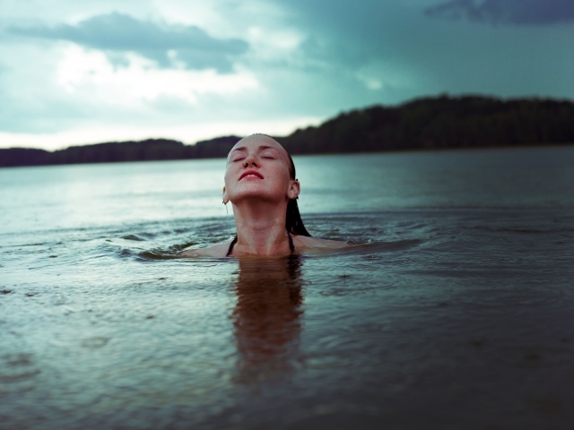 Молодая девушка купается в озере 