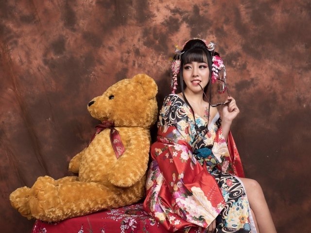 Девушка азиатка сидит с большим плюшевым медведем