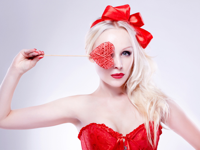 Красивая девушка блондинка в красном наряде с сердечком в руке