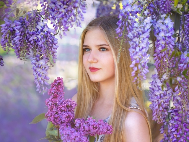 Красивая блондинка с букетом сирени на фоне цветов глицинии