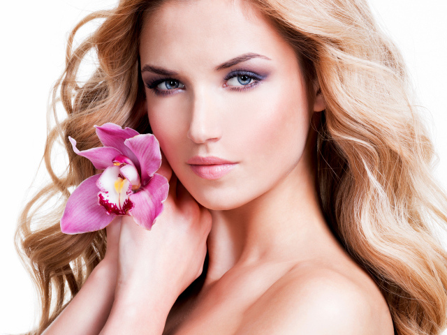 Красивая нежная блондинка с цветком орхидеи на белом фоне