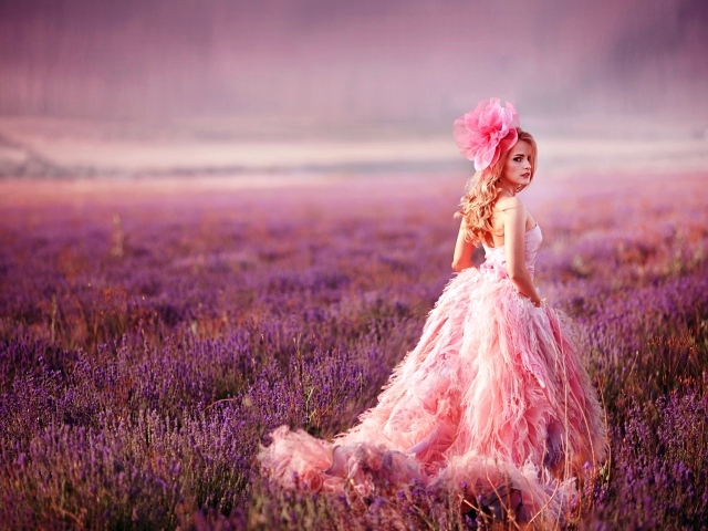 Красивая девушка в розовом платье гуляет по лавандовому полю