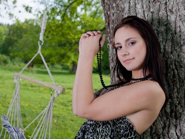 Красивая девушка с черными бусами под деревом