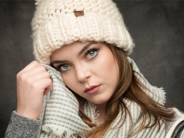 Красивая зеленоглазая девушка в белой вязаной шапке с шарфом