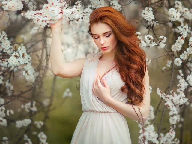 Красивая рыжеволосая девушка у цветущего дерева абрикоса 
