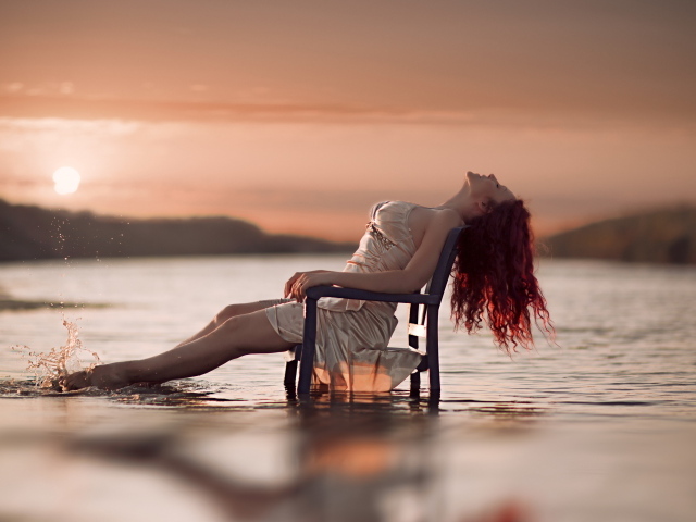 Красивая рыжеволосая девушка на стуле в воде