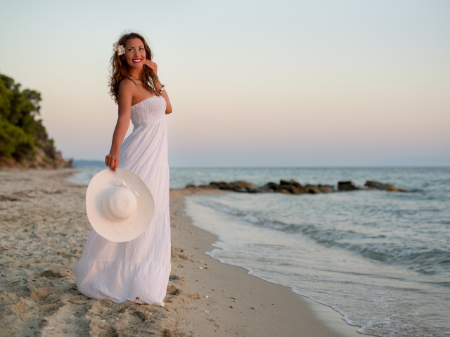 Красивая улыбающаяся девушка в белом платье на побережье