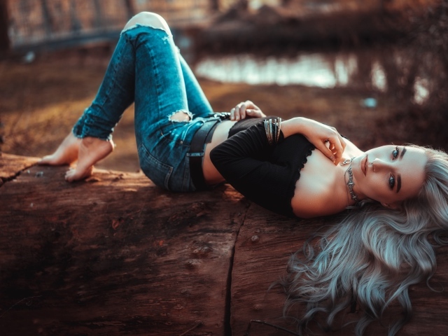 Красивая молодая блондинка лежит на сухом дереве