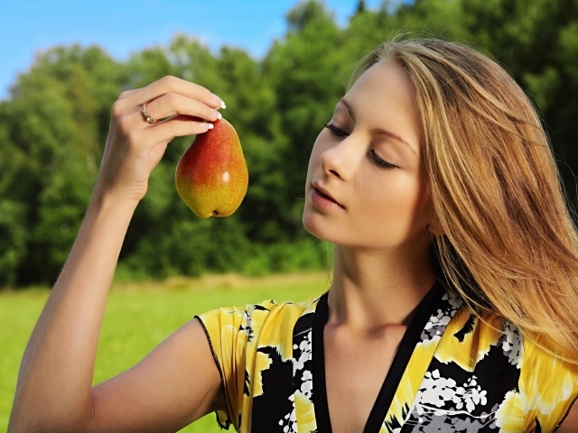 Красивая молодая девушка с грушей в руках