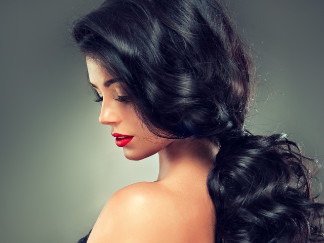 Девушка брюнетка с красивыми волосами на сером фоне
