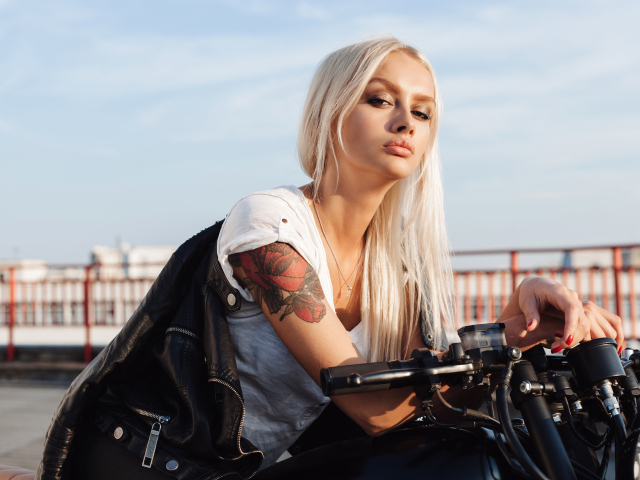Брутальная блондинка с татуировкой на руке на мотоцикле 