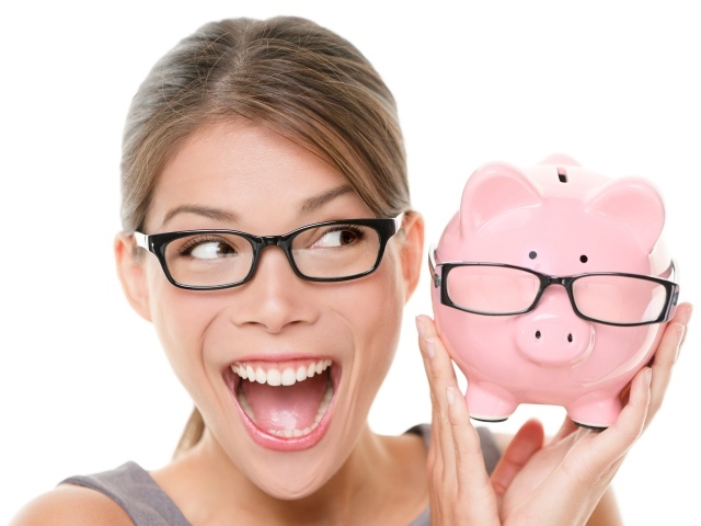 Веселая девушка в очках с копилкой в руках на белом фоне