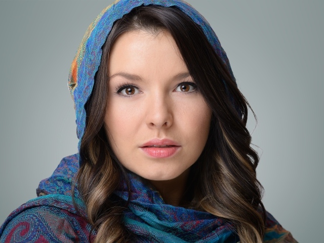 Лицо молодой кареглазой девушки в платке на сером фоне