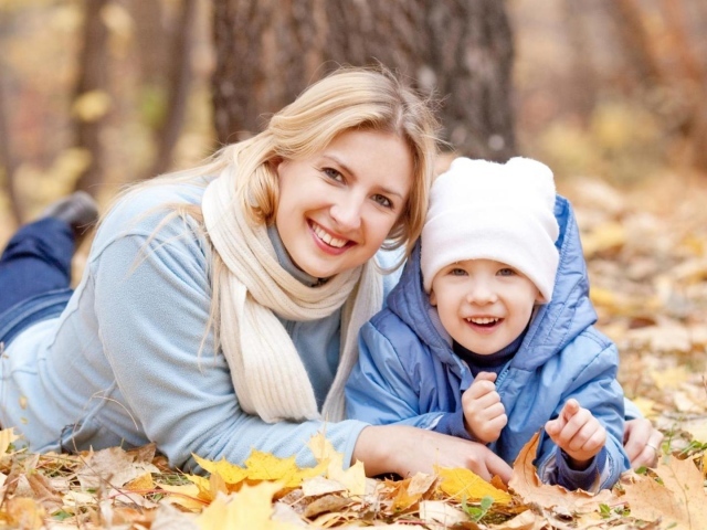 Мать с сыном лежат на листве осенью