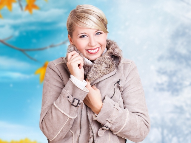 Улыбающаяся голубоглазая девушка в теплой куртке осенью 