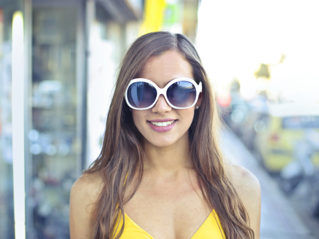 Улыбающаяся молодая девушка в солнечных очках 