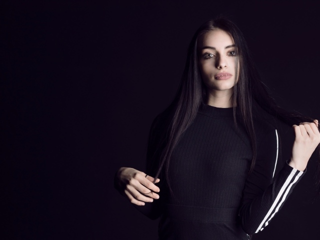 Эффектная брюнетка в черном наряде на черном фоне