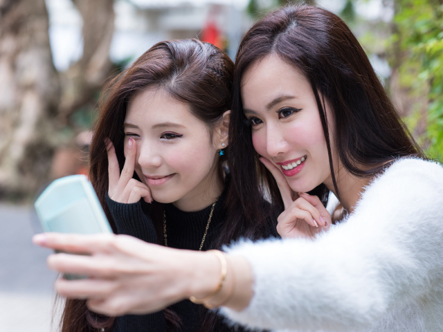 Две девушки азиатки делают селфи