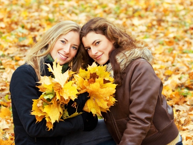 Две красивые девушки с желтыми листьями в руках